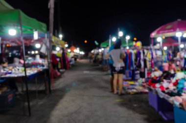 Soyut bulanık arkaplan, insanlar gece pazarından yiyecek ve mal almak için yürüyorlar..