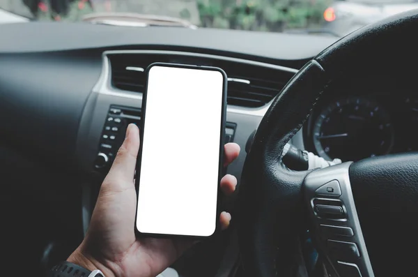 Driver holding a mobile phone in a mockup car with a white blank screen. A man watching a smartphone is searching for GPS navigator location information.Clipping path.Vintage tone