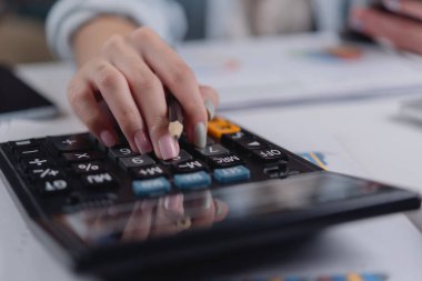 Female hand pressing calculator keys with documents. Great for financial planning, accounting, tax return, budget strategy, and business paperwork visuals.