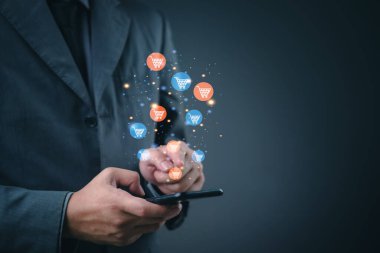 Businessman using smartphone for online shopping. Floating shopping cart icons represent mobile commerce and digital retail.