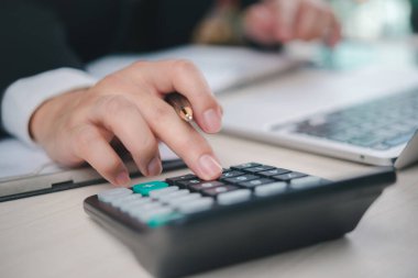 Finans verilerini hesap makinesi ve dizüstü bilgisayarla hesaplayan bir iş adamı. Muhasebe, vergi ve mali raporlar için bütçe planlaması ve finans analizi.