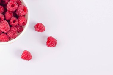 Beyaz arkaplanda bir fincanda ahududu, üst görünümde, metin için yeri var.