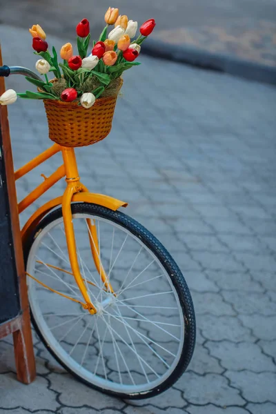 Bright orange bike with basket of flowers