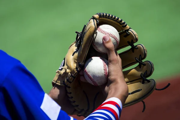 An arm stretches out to catch a baseball using a worn leather glove.