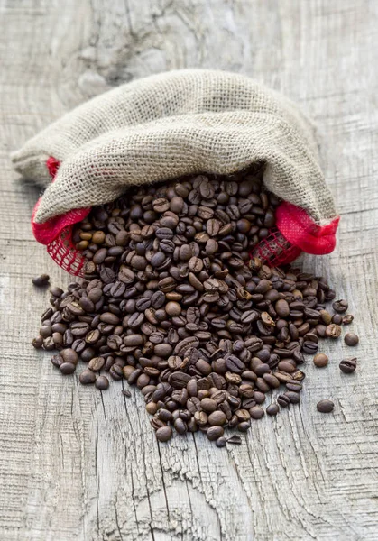 Coffee beans in coffee burlap bag on wooden surface