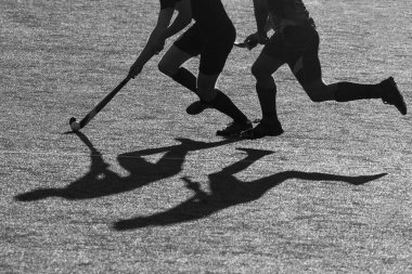 Siluet. Hokey oyuncuları gölgesi bir hokey sahasında bir hokey sopası ile çalışıyor.