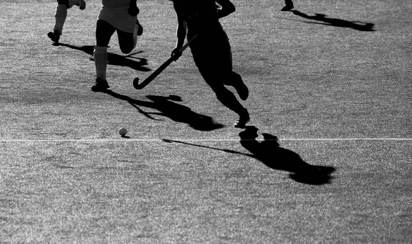 Silhouette. The shadow of a hockey players is running with a hockey stick on a hockey field.