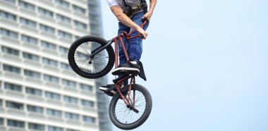 Bmx bisiklet üzerinde hile yapan erkek. BMX freestyle kentsel peyzaj zemin karşı.