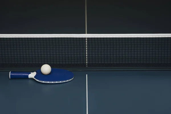 Raquettes de ping-pong et ballon et filet sur une table de ping-pong bleue — Photo