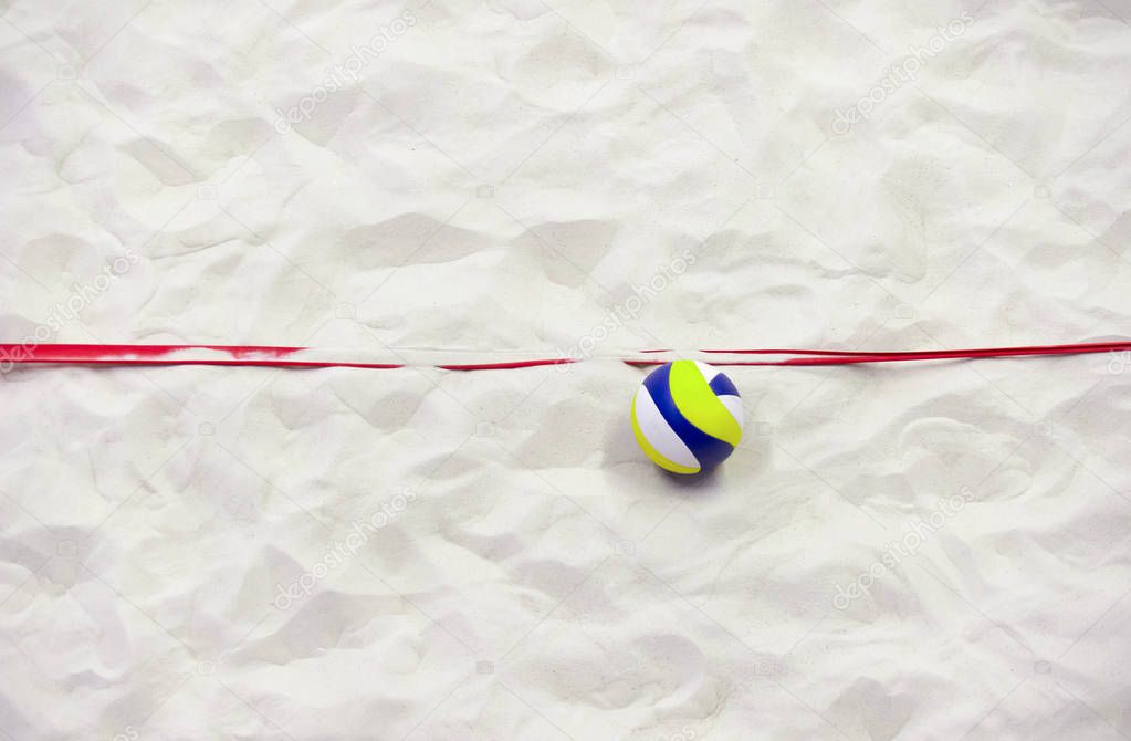 Colorful volleyball ball and red line on top of the sand.