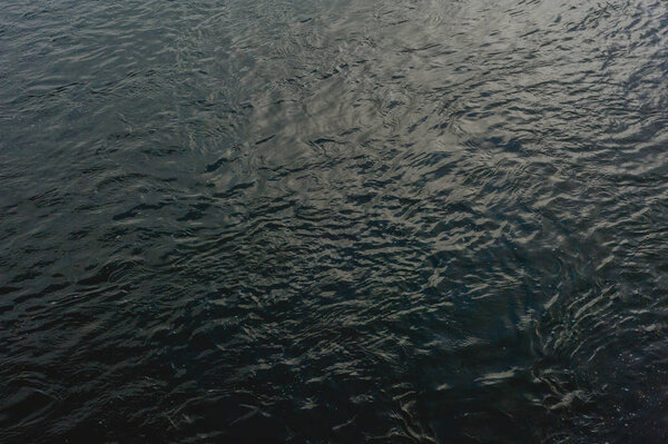 black peaceful sea background with ripples in water 