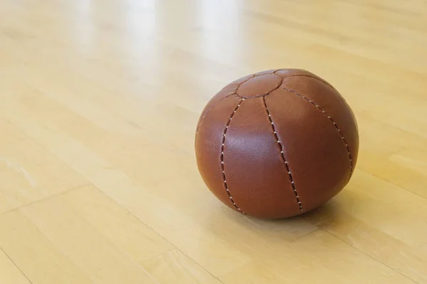 Brown medicine weight ball on wooden floor. Crossfit ball