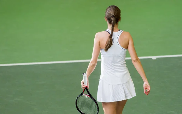 一个女网球运动员的背视图与球拍在行动 — 图库照片