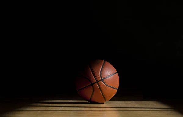篮球在球棒上黑色背景的实木复合地板 — 图库照片