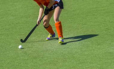 Genç bir hokey oyuncusu, top sahada rehine oynuyor.