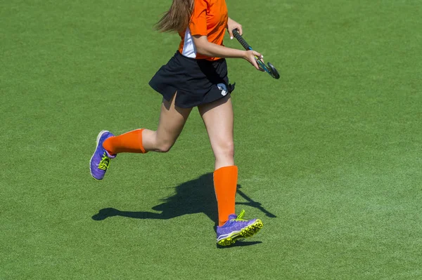 Field hockey player, in possesion of the ball, running over an a