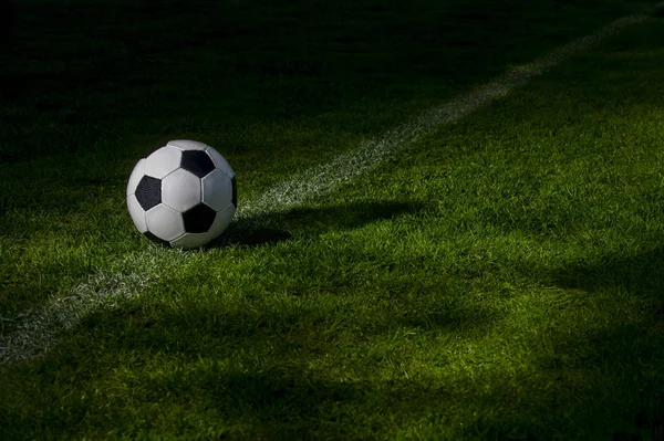 Black and white soccer ball on green soccer pitch