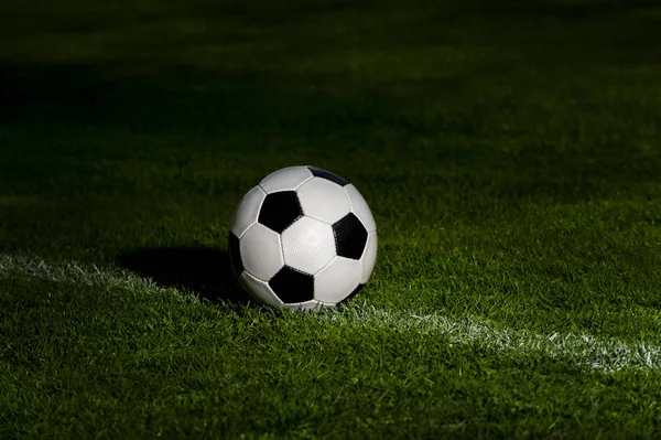 soccer ball classic in black and white on penalty spot on green artificial turf