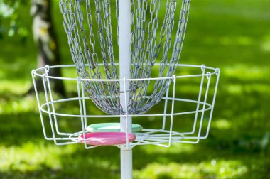 Parkın ortasında ki çimenlerde ve ağaçlarda metal golf sepeti. Sepet metal sepetiçine disk atarak frizbi golf oynamak için kullanılır