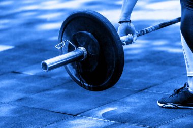 crossfit kadın ağır bir halter ile onu halter egzersiz için hazırlanıyor. Mavi renk