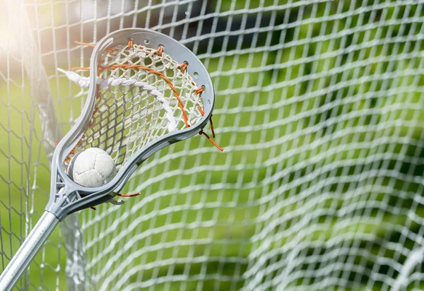 Abstract view of a lacrosse stick scooping up a ball. Sunny day