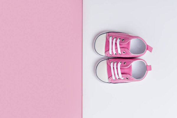 Cute pink baby girl sneakers close up on pink and white background