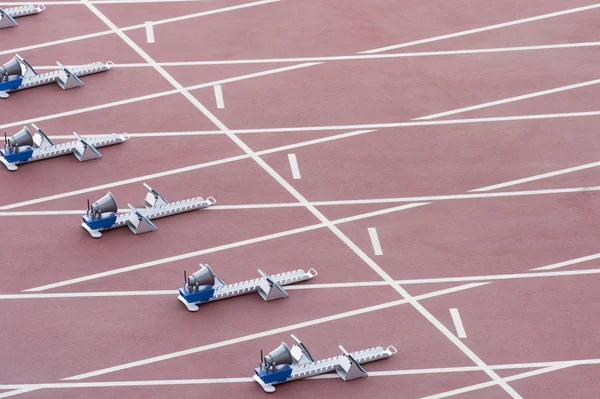 Athletic start block on dark red tartan track