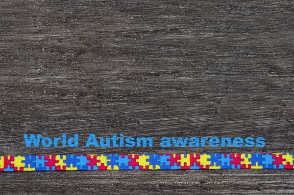 World Autism awareness day with Puzzle ribbon on wooden background