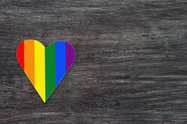 Gri ahşap arka planda gökkuşağı çizgili dekoratif kalp. LGBT gurur bayrağı, Lezbiyen, gay, biseksüel, transeksüel sembolü