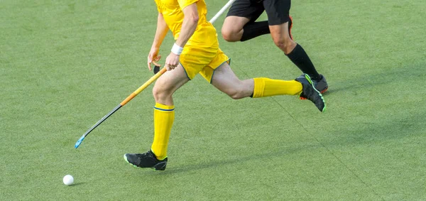 Two field hockey player, fighting for the ball on the midfield during an intense match on artificial grass