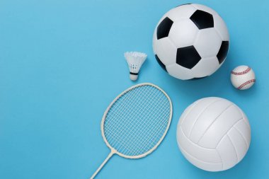 Açık mavi arka plan üzerinde basketbol, futbol topu, voleybol, beyzbol, badminton raket dahil olmak üzere çeşitli spor ekipmanları