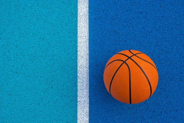 Оранжевый баскетбольный мяч на голубой поверхности — стоковое фото