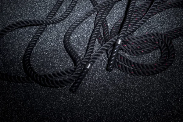 Close up of black battle rope on a gray backgound. Sport and fitness equipment. Functional training