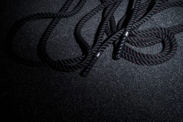 Close up of black battle rope on a gray backgound. Sport and fitness equipment. Functional training