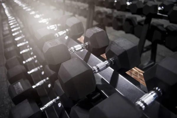 Close up many metal dumbbells on rack in sport fitness center