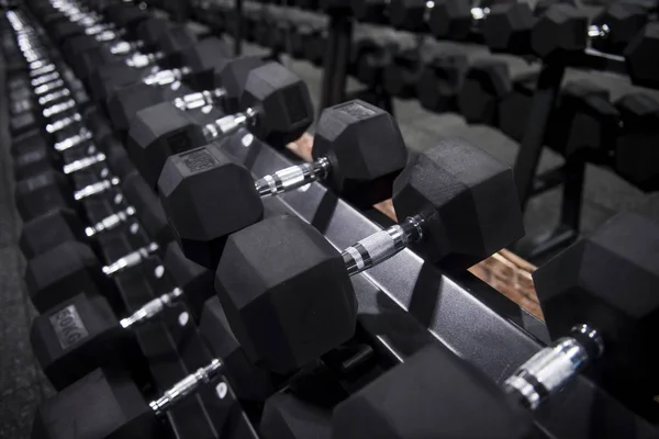 Close up many metal dumbbells on rack in sport fitness center