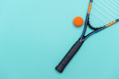 Mavi arka planda squash topu ve raketi yakın plan. Bireysel spor konsepti.