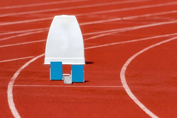 Athletic start block on dark red tartan track. Individual sport concept