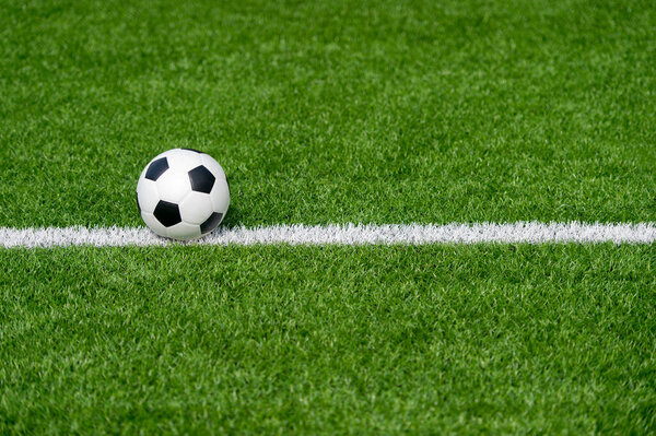 Черно-белый футбольный мяч в поле. Концепция командного спорта. Тренировки онлайн.