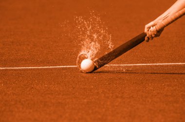 Çim hokeyi oynarken top oynayan hokey oyuncusu. Turuncu renk filtresi