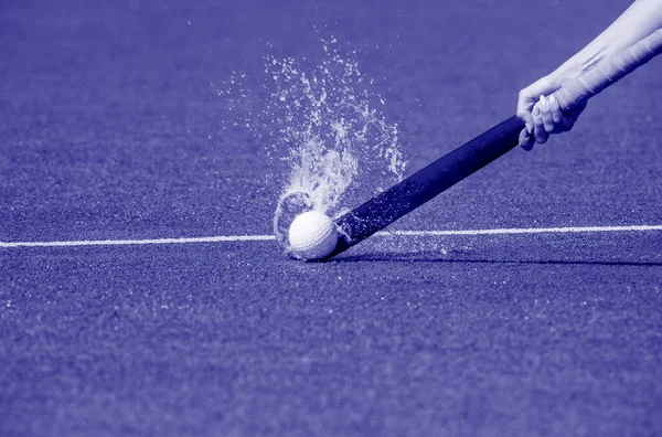 Hockey player with ball in attack playing field hockey game. Blue color filter