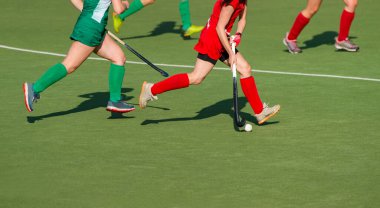 Üç kadın çim hokeyi maçında topun kontrolü için savaşıyor. Takım spor konsepti.