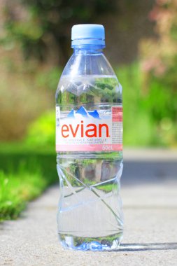 Güneşli yaz arkaplanlı bir şişe Evian doğal maden suyu.