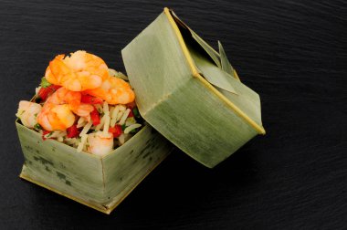Karides ve pirinç bambu yaprak kutularında kayrak taş zemin üzerine atmak