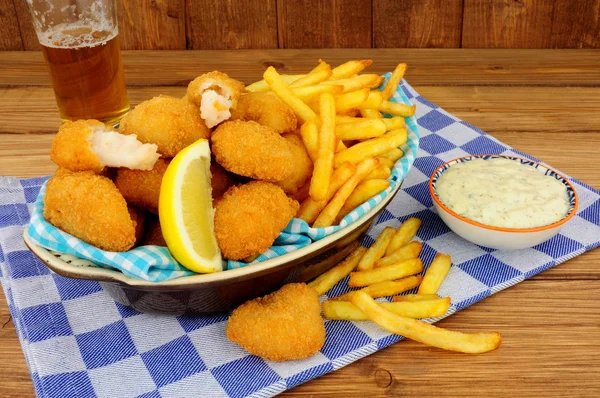 Scampi and French fries meal with tartar sauce on a wooden background