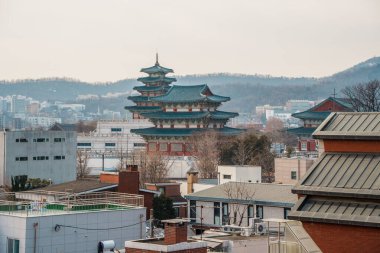 Elevated view of the National Folk Museum of Koreas pagoda with its blue tiled roof and rising above Seouls urban buildings and distant hills.