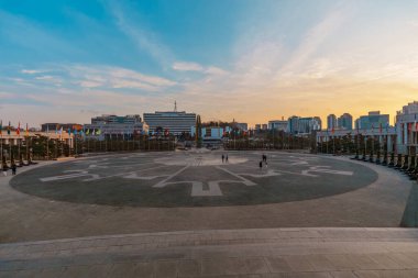 Sunset over the circular plaza at the War Memorial of Korea, Seoul, with flags surrounding the square .