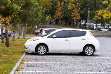 Odessa, Ukrayna - 12 Kasım 2018: gri kare kaldırım taşları ile işaretli beyaz çizgiler park yerleri, çim ve sonbaharda ağaçların çevresinde park yerinde Park beyaz Nissan Yaprak.