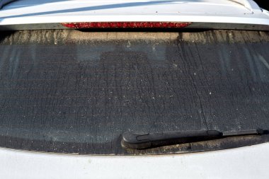 Kirli beyaz araba penceresinde toz, steyşın ısıtmalı penceresi ve silecek.