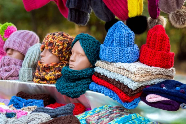Counter with knitted wool hats and colorful scarves with a mannequin head.